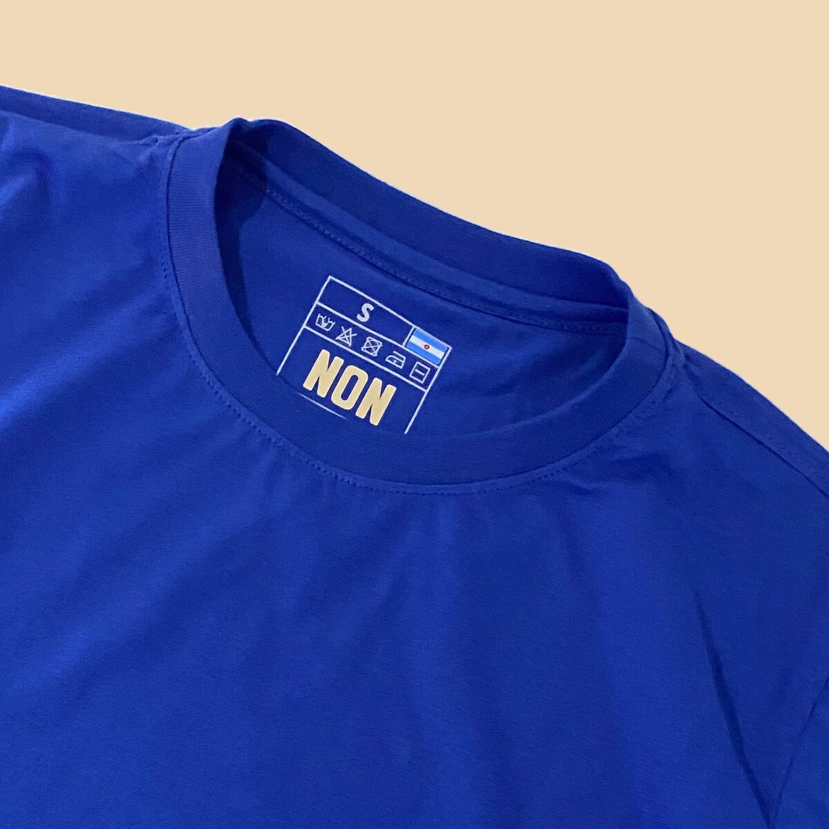 Detalle del cuello y etiqueta NON en la remera Azul Francia